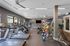 Modern fitness center with state-of-the-art treadmills, exercise bikes, and vibrant kettlebells set in a spacious, well-lit environment.