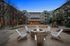 Elegant apartment courtyard with a cozy fire pit surrounded by Adirondack chairs, perfect for evening gatherings under string lights.