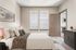 Inviting bedroom with elegant decor, featuring a plush bed with patterned throw, large windows for natural light, and a seamless entry to a cozy living area.