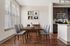 Modern dining area with elegant wooden table, chic gray chairs, and sophisticated kitchen in background featuring stainless steel appliances.