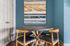 Chic dining area with a round wooden table, modern chairs, and abstract wall art against a stylish teal backdrop.