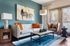 Chic living room with a contemporary white sofa, vibrant orange pillows, and horse artwork on a teal accent wall, featuring stylish rustic decor.