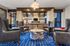 Luxurious living room featuring elegant leather chairs, a modern artistic coffee table on a vibrant blue patterned rug, and chic lighting accentuating the sophisticated decor.