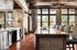 Elegant dining area with a modern kitchen island, featuring stylish patterned chairs and large windows offering a scenic view.