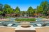 Luxurious apartment complex pool area featuring elegant sun loungers, vibrant greenery, and a central fountain, perfect for relaxation and leisure.