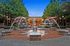 Vibrant courtyard featuring elegant water fountains and cozy seating under stylish canopies, framed by lush greenery and warm evening lights.