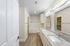 Modern bathroom with elegant granite countertops, dual sinks, and spacious bathtub, featuring stylish wood flooring and bright lighting.