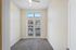 Bright room with plush carpet flooring, featuring a ceiling fan and large double doors leading to a balcony view.