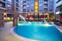 Luxurious apartment complex with a brightly lit, resort-style swimming pool and modern architecture, creating an inviting and vibrant living environment.