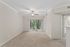 Bright and airy living room with plush carpeting, ceiling fan, and large sliding doors leading to a scenic balcony view.