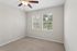 Bright, inviting room with plush carpeting, dual windows for natural light, and a stylish ceiling fan offering comfort and elegance.