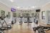 Bright and airy gym room equipped with modern exercise machines, motivational wall quotes, and large windows providing a serene outdoor view.