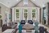 Elegant living room with high vaulted ceilings, large windows with outdoor views, modern decor, and plush seating for relaxation.