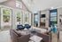 Elegant living room with high ceilings, large windows, and a stunning fireplace, featuring stylish seating and modern decor.