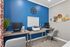 Modern home office setup featuring dual desks with computers, vibrant blue accent wall, stylish decor, and inviting natural light.