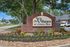 Inviting entrance sign for The Villages of Cypress Creek, surrounded by lush trees and vibrant landscaping.