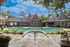 Charming brick clubhouse with elegant pool and lush landscaping, perfect for relaxation and social gatherings.