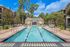 Inviting swimming pool area surrounded by lush trees and elegant brick buildings, perfect for relaxation and enjoyment.