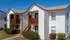 Charming two-story apartment complex with modern white brick exterior and inviting wooden balconies under a clear blue sky.