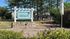 Inviting entrance to Creekwood North Apartment Homes surrounded by lush greenery and tall pines.