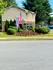 Inviting entrance of Garden Cove apartment homes with lush greenery, colorful flags, and a welcoming atmosphere.