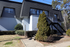Charming apartment building with modern black and white exterior, featuring an inviting entrance and lush greenery.
