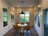 Chic dining area with modern amber chairs, elegant round table, and stylish wall art, featuring bright windows and contemporary lighting.