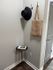 Chic entryway with a stylish black hat and woven tote hanging on hooks, complemented by a sleek round side table and a decorative book, radiating warmth and sophistication.