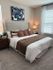 Inviting bedroom with plush bedding, a cozy ambiance, and stylish decor, featuring modern art and elegant lighting.
