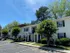 Charming two-story apartment building with classic white siding, surrounded by lush greenery and blue skies, offering a serene residential ambiance.