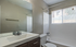 Modern, well-lit bathroom with a sleek vanity, large mirror, and a pristine bathtub, perfect for relaxation.