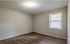 Bright and cozy room with soft carpet flooring, large window with blinds, and neutral walls perfect for personalization.