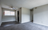 Inviting apartment interior featuring a bright room with a ceiling fan, fresh carpeting, and ample natural light from a large window.