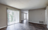 Bright living space with elegant laminate flooring and large sliding glass doors opening to a lush green view.