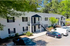 Charming two-story apartment building with classic architecture, surrounded by lush greenery and convenient parking.