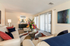 Bright, cozy living room with modern decor, vibrant floral centerpiece, and ample natural light through large windows.