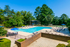 Inviting outdoor pool area surrounded by lush greenery and sun loungers, perfect for relaxation and leisure.