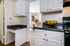 Charming kitchen with white cabinets, sleek countertops, and a cozy view into a dining area with vibrant floral centerpiece.
