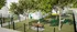 Charming apartment dog park with lush greenery, seating areas, playful tubes, and spacious fenced grounds for pets to roam.