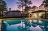 Charming apartment complex with a stunning swimming pool, surrounded by lush trees at sunset.