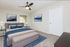 Inviting bedroom featuring a plush bed with elegant blue accents, modern ceiling fan, and serene mountain artwork.