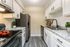 Modern kitchen with sleek stainless steel appliances, elegant white cabinets, and vibrant decor including fresh tomatoes and lush green plants.