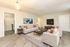 Inviting modern living room with plush white sofas, sleek TV unit, and open access to the stylish kitchen.