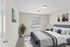 Bright, elegant bedroom with modern decor, featuring a plush bed, artistic paintings, and a large window inviting natural light.