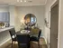Contemporary dining area with elegant dark wood furniture, large mirror, and stylish decor, adjacent to a modern kitchen.