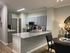 Modern kitchen and dining area in an open-concept apartment, featuring sleek gray cabinetry, a stylish granite countertop, and contemporary decor.