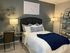 Modern bedroom featuring a cozy bed with elegant navy accents, stylish wall decor, and ambient lighting for a serene atmosphere.