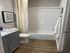 Modern bathroom with sleek design featuring a refreshing bathtub-shower combo, elegant vanity with granite countertop, and stylish wooden flooring.