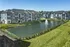 Charming apartment complex with scenic pond and elegant architectural design, featuring a beautiful fountain.