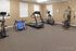 Inviting fitness room featuring modern exercise equipment, including a treadmill, stationary bike, elliptical, and strength training machine, all in a bright, well-lit space.